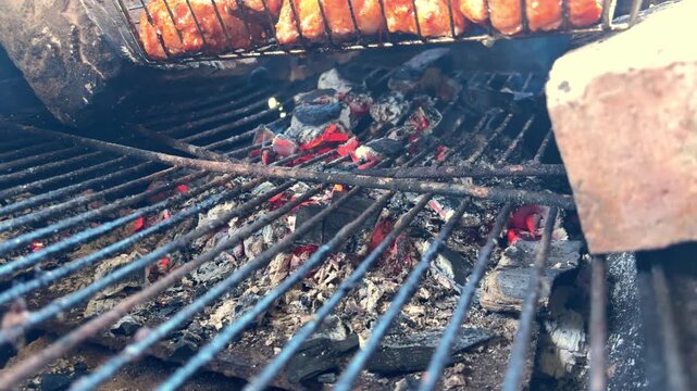 Smoldering charcoal coals glowing inside a barbecue grill, outdoor cooking, backyard barbecue, summer grilling, heat and fire.