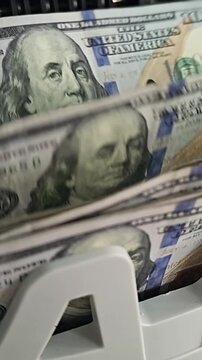 Counting cash in a bank with hundred dollar bills on a money counting machine