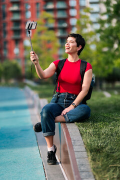 Woman in red taking outdoor selfie with stick