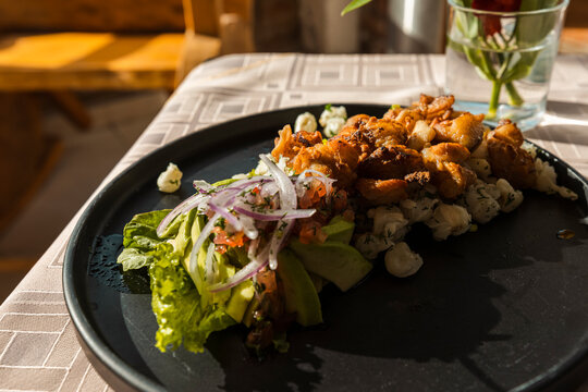 Gourmet presentation of traditional mote with crispy pork chicharron, avocado, and fresh onions