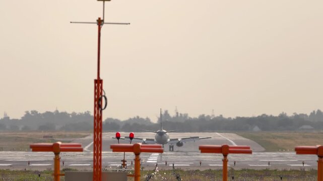 Passenger airplane braking on runway after landing with spoilers deployed, telephoto shot showing strong heat haze and atmospheric distortion.