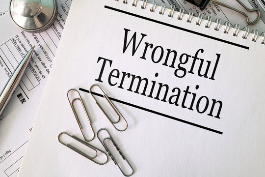 Wrongful Termination text on notebook with pen and paperclips on white background, labor law and employment concept