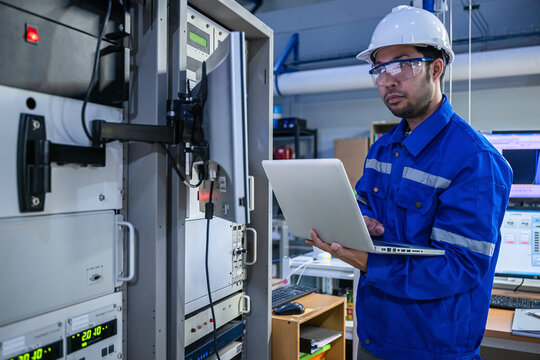 Electrical engineer male checking voltage at the Power Distribution Cabinet in the control room,preventive maintenance Yearly,inspecting power system and control panel in industrial factory