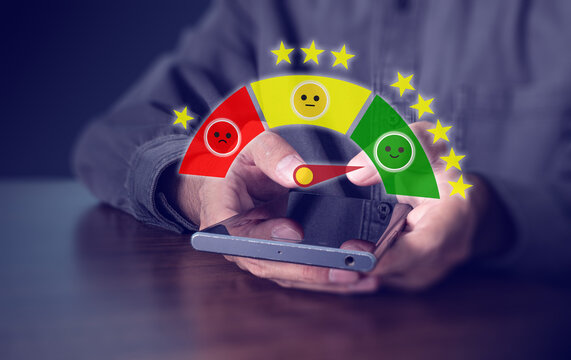 Hand holding smartphone with colorful customer satisfaction rating gauge and stars, feedback and review concept