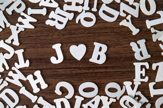 JOB word with heart symbol spelled with letter tiles on scattered letters wooden background, employment and career concept