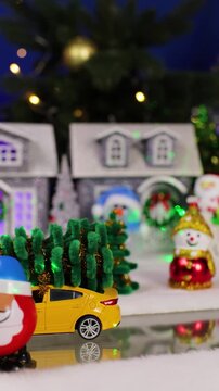 A yellow car passes snowmen in a Christmas town