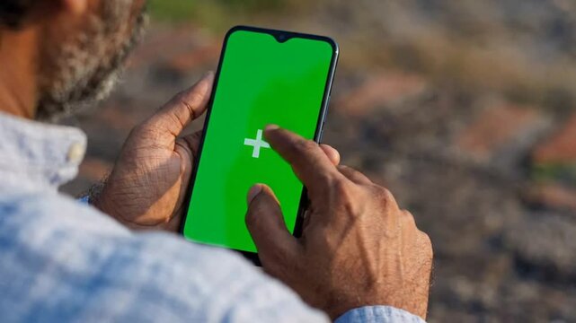 Man using smartphone with green screen chroma key display for app interaction and digital customization