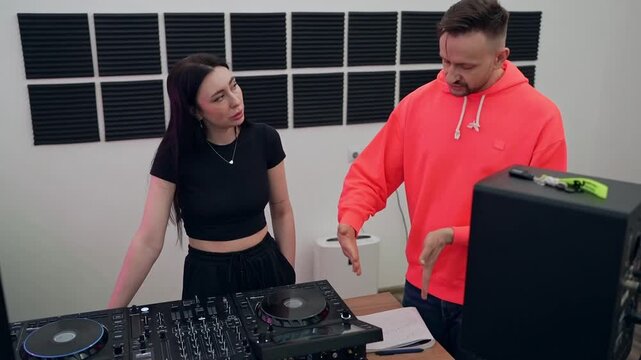 DJs collaborating in large white studio mixing music on DJ controllers and turntables. DJ, collaboration, studio, music, controllers, turntables