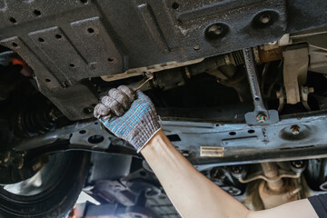 Fototapeta premium Mechanic repairing car engine in auto repair shop. Auto service and maintenance