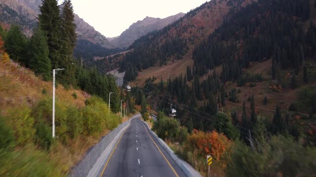 Flying over a mountain road with funiculars. A beautiful road with a funicular in the mountains in autumn.