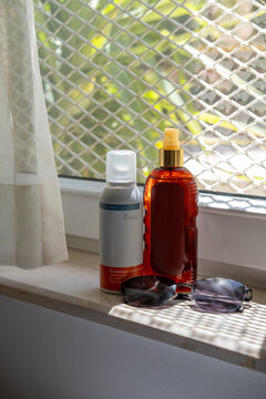 Sun care products and sunglasses placed on a hotel room windowsill during a summer vacation