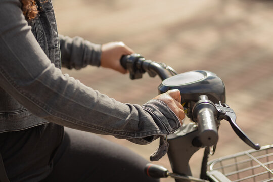 Close-up of hands turning the ignition key to start an electric bicycle, representing sustainable daily commuting to work.