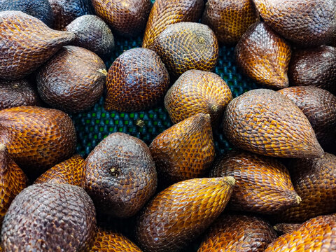 Fresh salak fruits arranged in a tray for sale, showcasing their distinctive scaly brown skin, natural variation in color, and abundant tropical produce at a local market.