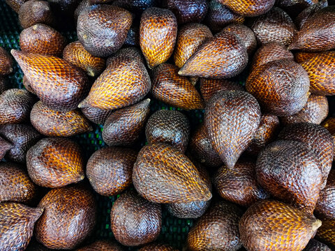 Fresh salak fruits arranged in a tray for sale, showcasing their distinctive scaly brown skin, natural variation in color, and abundant tropical produce at a local market.