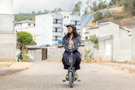 Young Black Brazilian woman riding an electric bicycle during her daily commute, representing modern urban mobility, practical transportation, and sustainable mobility.