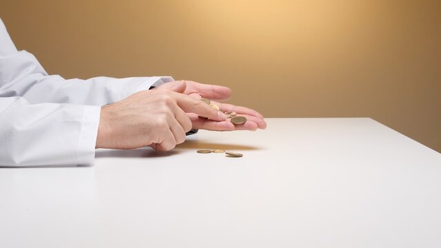 Medical professional's hands in a lab coat checking small coins, symbolizing current high healthcare costs, medical fees, and the importance of budgeting
