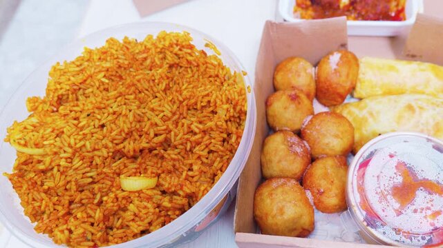 West African jollof rice with puff puff and meat pie takeout box