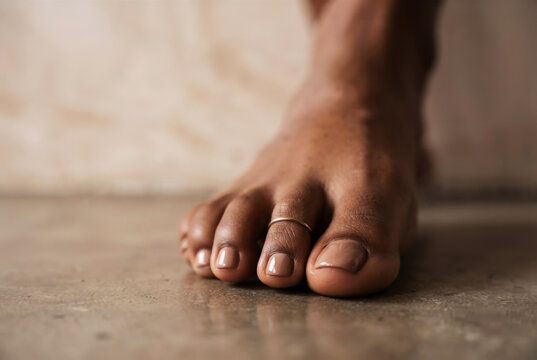 Close Up of Pedicured Feet with Minimalist Gold Toe Ring on Concrete Floor