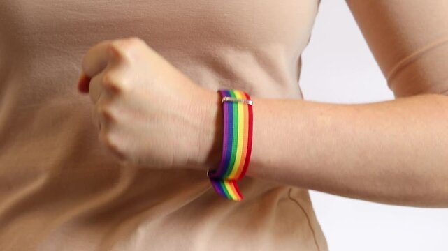 Clenched fist with rainbow bracelet on hand as a symbol of confidence and inner strength. Close-up of a woman's hand clenched into a fist with a bright rainbow-colored textile strap. LGBTQ+