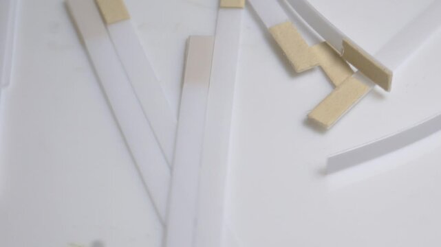 Close-up of white medical test strips with indicator pads rotating on a turntable under bright studio lighting.