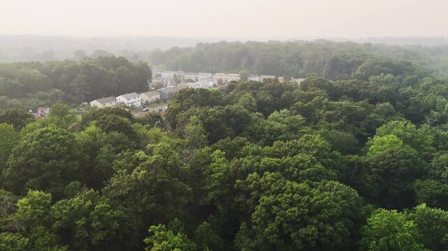 Drone view of dense smoke covering a residential forest landscape in the USA, representing wildfire, air pollution, climate crisis, and environmental damage.