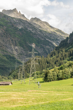Guttannen, Switzerland. High-voltage transmission towers crossing an alpine valley beneath rugged mountain peaks in the Bernese Oberland