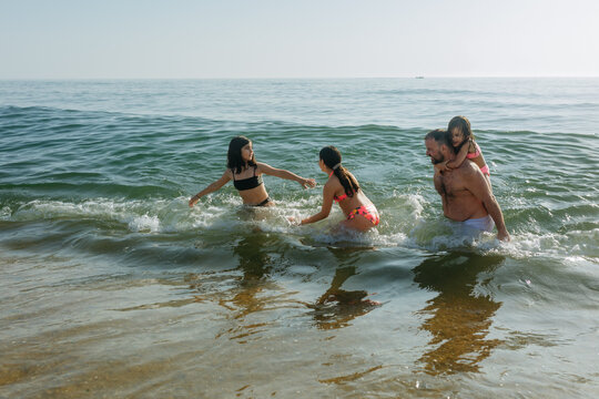 Father and Daughters Playing in Ocean Waves During a Summer Beach Day