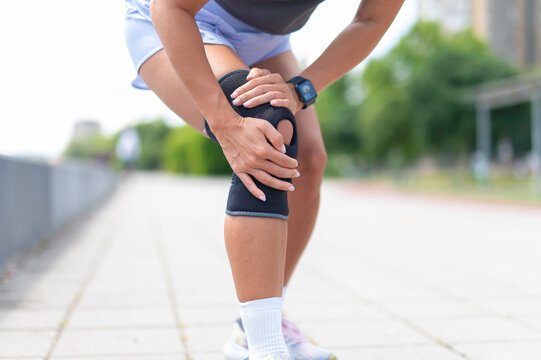 Female runner experiencing knee pain wearing a brace