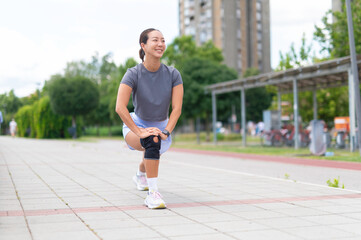Obraz premium Asian woman stretching legs with knee brace outdoor
