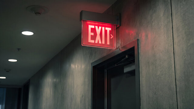 Red exit sign in dark corridor hallway illuminated for emergency safety concept