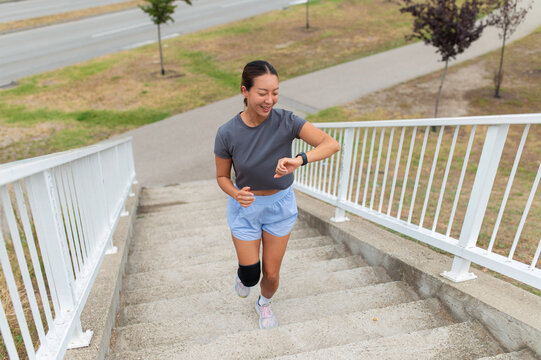 Woman jogging up stairs checking fitness tracker