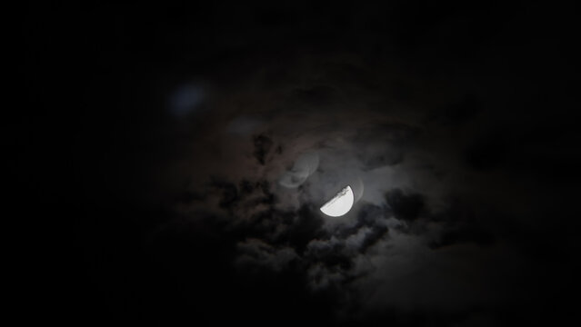 view of a half moon in a cloudy sky at night