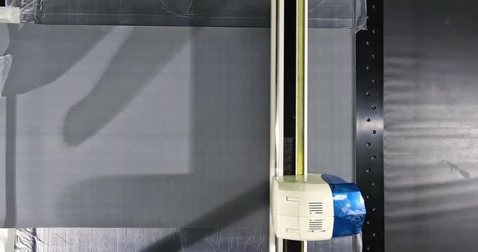 CNC Fabric Cutting Process in Modern Manufacturing Workshop. Automated Textile Cutting on CNC Plotter Machine. Digital cutting system (automatic cutting plotter) in operation.
