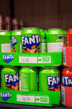  Green aluminium cans of Fanta Exotic soft drink stacked in display trays on a supermarket shelf.