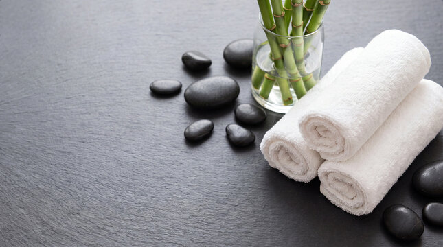 Spa background with bamboo and rolled white towels on stone