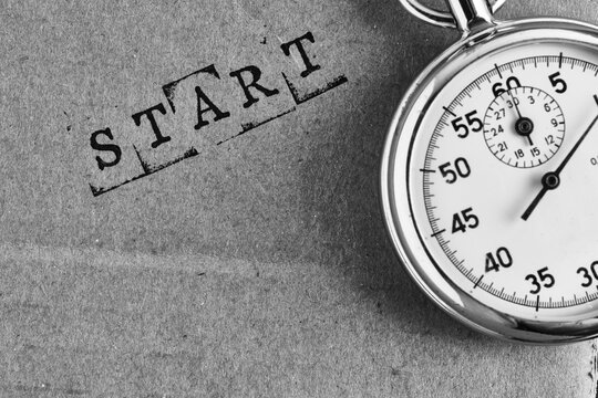 Vintage stopwatch on paper with stamped word START, symbolizing new beginnings and time management.