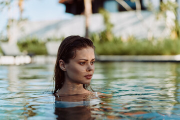 Fototapeta premium A woman calmly floats in a sunlit pool, head and shoulders above water, conveying relaxation and lifestyle leisure. Warm light, tranquil surface, and reflective water create a serene moment.