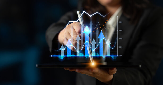 A business professional uses a stylus on a tablet to analyze digital graphs and charts showing growth and trends in a contemporary office, showcasing modern technology in action. Scalp
