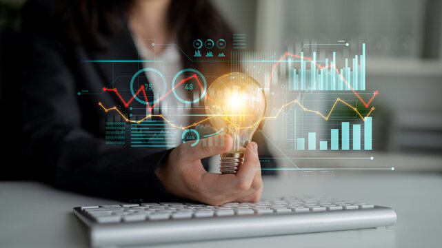 A business professional holds a light bulb representing innovative ideas amidst data analytics and charts, highlighting the intersection of creativity and technology in the modern workplace. Scalp