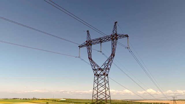 Metal electricity pylon in agricultural field, high voltage power line transmission and energy infrastructure concept
