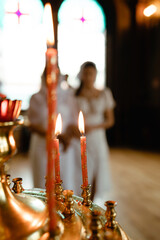 Obraz premium Burning candles inside a Christian church during a baptism ceremony. Warm candlelight and soft focus create a peaceful spiritual atmosphere, symbolizing faith, prayer, 