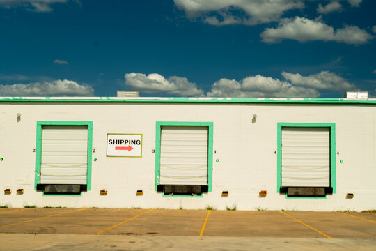Industrial Shipping and Receiving Truck Dock Garages of Industrial Factory Building With Shipping Sign With Cloudy Blue Sky