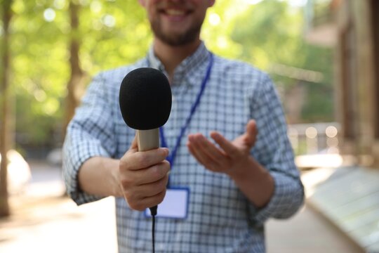 Professional journalist with microphone working outdoors, closeup