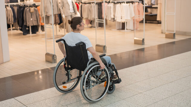 A Caucasian woman in a wheelchair shopping at a mall. 