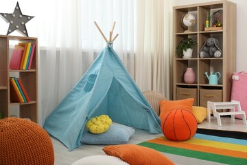 Blue wigwam, colorful pillows and shelving unit in stylish child's room. Interior design © New Africa