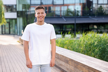 Obraz premium Young man wearing stylish white t-shirt outdoors, space for text