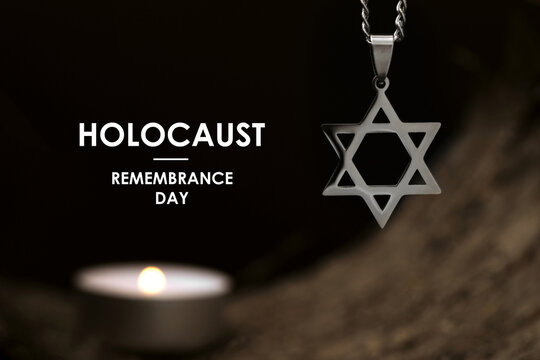 Holocaust Remembrance Day. Star of David pendant and candle on tree bark, selective focus