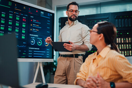 It professional discussing server room data management and monitoring with female colleague in data center