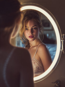 Woman looking at her reflection in glowing ring light mirror