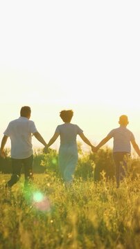 happy family run, parents man woman holding children hands sunset park, mother father parents kid outdoors nature, peaceful family time outdoors, sunlit silhouettes of children together, community